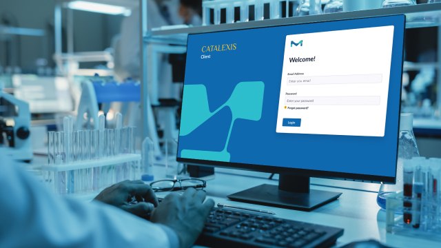Catalexis Service Page 화학자는 눈에 보이지 않지만 첨단 기기가 잘 갖춰진 화학 실험실에서 Catalexis 로그인 화면을 보고 있습니다.