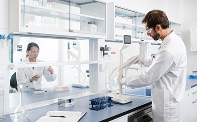 Q-POD Ultrapure Water Dispenser A laboratory scene showing two scientists in white lab coats working with lab equipment, including two Q-POD ultrapure water dispenser and various glassware.
