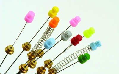 Nitinol-core SPME fiber La imagen parece una colección de coloridos alfileres y resortes metálicos. Las cabezas de los alfileres son de plástico y de color rosa, verde y amarillo, entre otros.