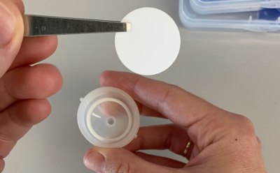 Swinnex<sup>®</sup> Filter Handling Fotografía de las manos de una persona utilizando pinzas para manipular un disco de filtración.