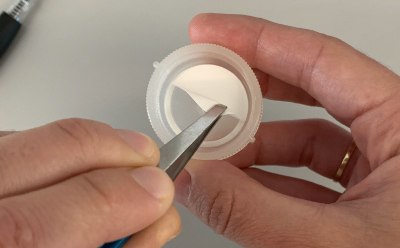 Swinnex<sup>®</sup> Filter Placement Fotografía de las manos de una persona utilizando pinzas para colocar un disco de filtración.
