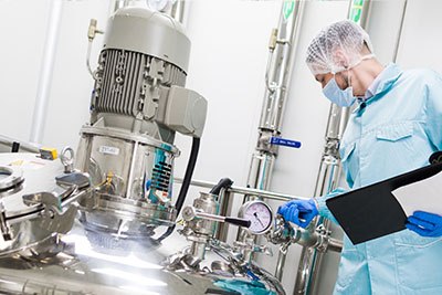 kosher-manufacturing Quality control professional in protective gear conducting an inspection of Kosher food processing machinery, ensuring adherence to strict cleanliness and manufacturing standards.