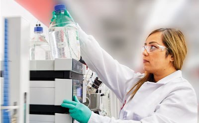 Purification of DNA and RNA oligos Female researcher in lab coat and gloves operating an HPLC during analysis of oligos
