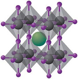 A 3D representation of a crystal lattice structure. The lattice consists of interconnected tetrahedral units, with black spheres representing one type of atom, purple spheres representing another type, and a large green sphere positioned in the center, indicating a different atom or ion. The arrangement illustrates the geometric symmetry and spatial organization of the atoms within the crystal framework.