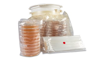 IsoBag® Rapid Transfer Solution including transport bags and culture media plates A collection of sealed bags containing various petri dishes and a flat tray, all arranged together, highlighting the sterile packaging and preparation for laboratory use.