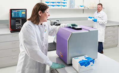 Custom Assay Development & Innovation (CADI) Services Two scientists in a lab performing immunoassay work on the SMCxPRO® instrument with the Luminex® xMAP® INTELLFLEX® instrument in the background.